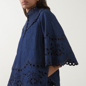 Model wearing Zimmermann blue cotton top with broderie anglaise cut-out detailing, scalloped hem, and wide sleeves