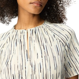Model wearing Whistles cream printed dress with keyhole neckline and short sleeves, close-up showing vertical brushstroke print detail