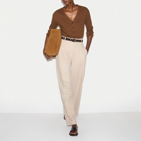 Model wearing Jigsaw brown knit cardigan with cream wide-leg trousers and brown belt, carrying tan suede clutch bag.