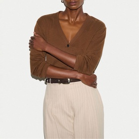 Model wearing Jigsaw brown V-neck knit top, styled with cream pinstripe trousers and a brown leather belt.
