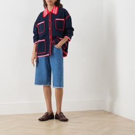 Model wearing Essentiel Antwerp navy cardigan with pink contrast trim and patch pockets, styled with denim culottes and brown loafers.