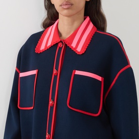 Model wearing Essentiel Antwerp navy cardigan with red trim, striped pink and red collar, and patch pockets, shown in close-up crop