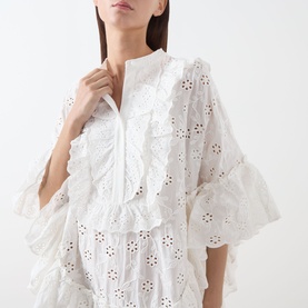 Model wearing Essentiel Antwerp white cotton broderie anglaise dress with ruffle trim and flared sleeves, close-up detail view