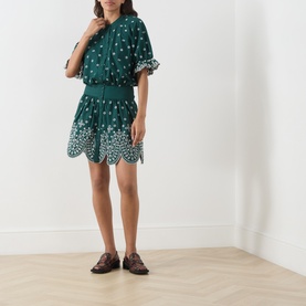 Model wearing Essentiel Antwerp bottle green cotton mini dress with white floral embroidery, styled with brown loafers.