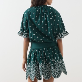 Model wearing Essentiel Antwerp bottle green cotton dress with all-over print, frill sleeves and scalloped hem, seen from behind.