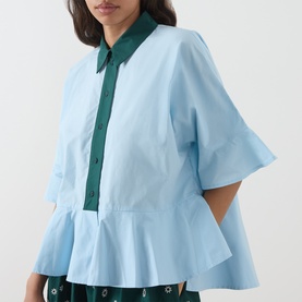 Model wearing Essentiel Antwerp aquamarine cotton shirt with green collar and button placket, flared hem and short flutter sleeves