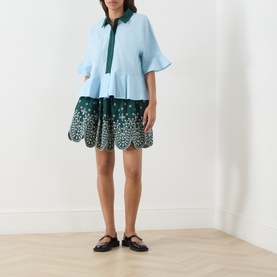 Model wearing Essentiel Antwerp aquamarine cotton shirt with fluted sleeves and dark green embroidered hem, styled with matching skirt and black