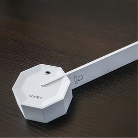 Gingko white desk light with geometric octagonal base and slim extending arm, shown on dark wooden surface