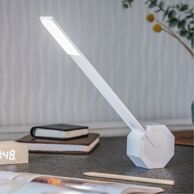 Gingko white desk light with angled LED arm and geometric hexagonal base, styled on a desk with books and a clock