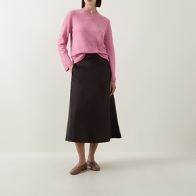 Model wearing InWear Chocolate Brown midi skirt with flared hem, styled with a pink crew-neck knit jumper and tan flat shoes.