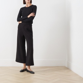 Model wearing InWear black wide-leg cropped trousers, styled with a black long-sleeve top and black flat shoes.