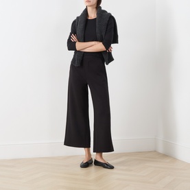Model wearing InWear black wide-leg cropped trousers, styled with a black top and grey knit scarf, paired with black flat mules.