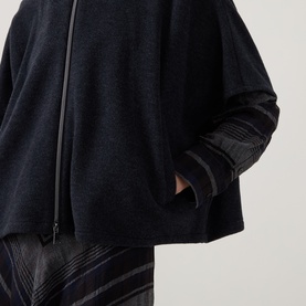 Model wearing Luisa Cerano anthracite knitwear with zip detail and contrast woven sleeves, styled with dark check trousers.