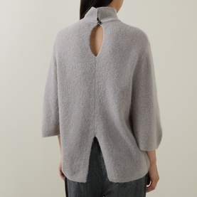 Model wearing Luisa Cerano pearl alpaca-blend knit sweater, back view showing keyhole neckline detail and split hem, styled with dark trousers.