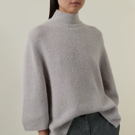 Model wearing Luisa Cerano pearl alpaca-blend knit sweater with mock turtleneck and relaxed fit, styled with grey wide-leg trousers