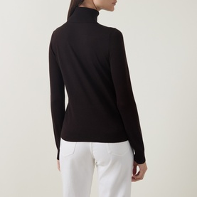 Model wearing Luisa Cerano Solid Turtleneck Sweater in Truffle, fine knit with long sleeves, styled with white trousers. Back view.