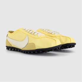 Nike soft yellow and pearl low-top trainers with white Swoosh, nylon upper, and black rubber sole, shown as a pair angled view