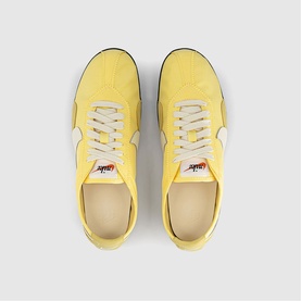 Nike trainers in soft yellow and soft pearl, overhead flat-lay view, white laces, black trim, textured suede-style upper