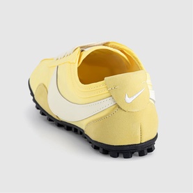 Nike trainer in soft yellow and soft pearl, nylon upper with white Swoosh detail, black rubber outsole, rear three-quarter view