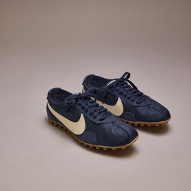 Nike Waffle Racer trainers in midnight navy and soft pearl, featuring cream Swoosh, leather upper, and tan multi-stud sole
