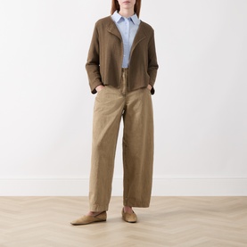 Model wearing Masai Slate Black cardigan with light blue shirt, wide-leg beige trousers and tan loafers