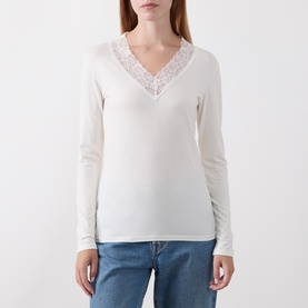 Model wearing Masai cream long-sleeve top with V-neck lace trim detail, styled with blue jeans.