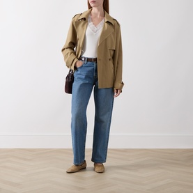 Model wearing Masai cream top styled with tan cropped jacket, blue straight-leg jeans, and taupe loafers, small burgundy bag