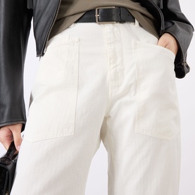 Model wearing Nili Lotan Vintage Cream trousers with patch pockets, styled with a black leather jacket and belt.