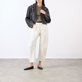 Model wearing Nili Lotan Vintage Cream wide-leg trousers, styled with a black leather biker jacket and black flat shoes.