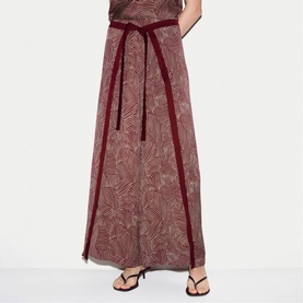 Model wearing Jigsaw red printed maxi skirt with velvet tie belt and contrast trim, styled with black strappy sandals