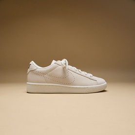 Nike low-top trainer in sail white leather with perforated Swoosh detail, white laces, and cream flat sole