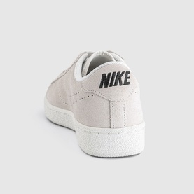 Nike trainer in sail white suede with black branding, white sole, shown from rear three-quarter angle