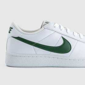 Nike trainer in white leather with green Swoosh logo, white sole, lace-up fastening, low-top silhouette