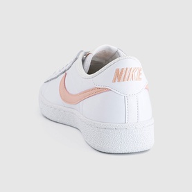 Nike trainer in white with Arctic Orange swoosh and metallic logo detail, smooth leather upper, white sole, rear angle view