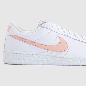 Nike trainer in white leather with arctic orange Swoosh logo, flat white sole, low-top silhouette