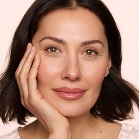 Model with Trinny London The Lip Reset Kit, showcasing a natural makeup look with glossy pink lips and glowing skin
