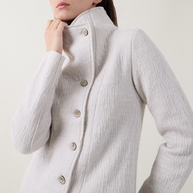 Model wearing Transit white 100% virgin wool coat with high stand collar and pearl-effect button fastening, textured knit detail visible
