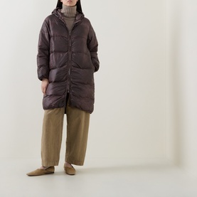 Model wearing Transit rust hooded quilted longline puffer coat, styled with khaki wide-leg trousers and tan loafers