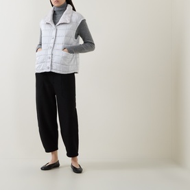 Model wearing Transit ice quilted gilet with grey roll-neck, black tapered trousers and flat black loafers.
