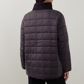 Model wearing Transit quilted silk jacket in Choco, shown from behind with box-quilt pattern and high collar detail.