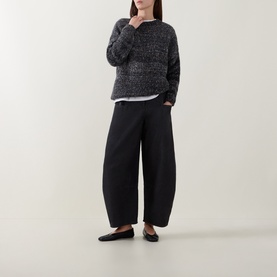 Model wearing dark grey marled knit sweater with wide-leg black trousers and black flat shoes