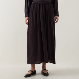 Model wearing Transit choco gathered midi skirt in 100% virgin wool, styled with black Mary Jane flats and long-sleeve top.