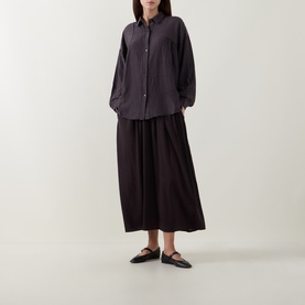 Model wearing Transit Choco wool skirt with matching dark shirt and black Mary Jane flats. Full-length gathered silhouette.