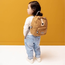 Toddler wearing Trixie brown bear character mini backpack with embroidered face detail, styled with white top and blue jeans
