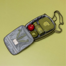 Trixie green dinosaur lunch bag open, showing grey insulated interior packed with matching green containers and a red apple