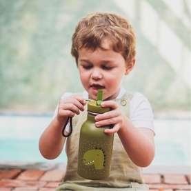 Young child drinking from Trixie green water bottle with dinosaur motif, straw lid and carry strap