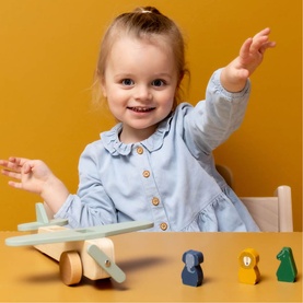 Young child playing with Trixie wooden toy aeroplane set in multi colours, with small animal figures displayed alongside