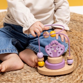 Trixie multi-coloured wooden bead maze toy with hedgehog motif, yellow and purple beads, in use by a young child