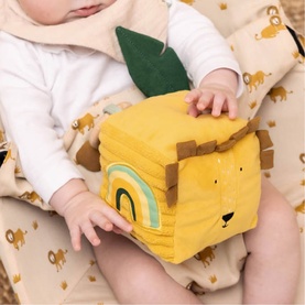 Trixie orange lion soft activity cube toy held by a baby, featuring rainbow and face detail on yellow fabric panels