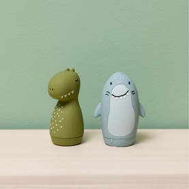 Trixie stacking toys in green dinosaur and blue dolphin character designs, displayed on a shelf against a sage green background